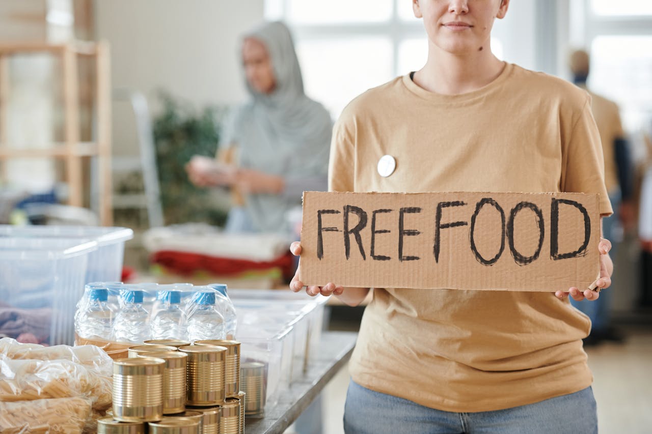 services-03 Volunteer holding a free food sign at a donation center, promoting charity and aid.