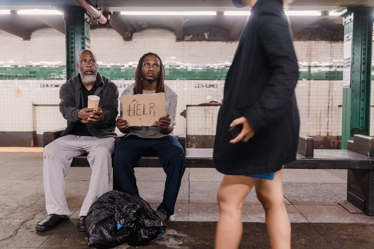 about-us Two men seeking help at a subway platform, highlighting urban poverty and social issues.